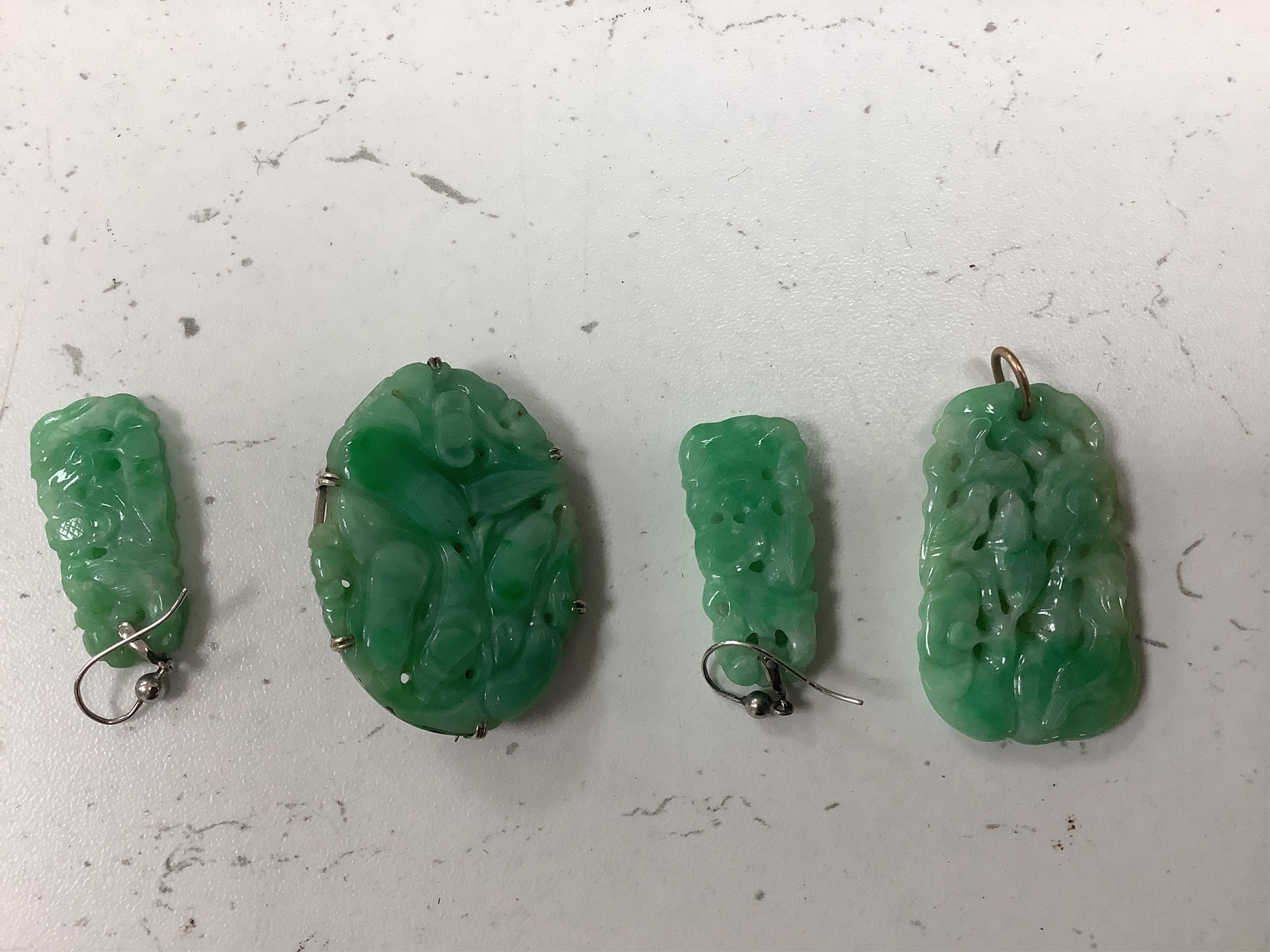 Four items of white metal mounted carved jade jewellery, comprising a brooch, 37mm, a pendant and pair of earrings.